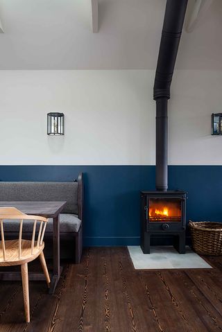 Interior of the Kinneuchar Inn, Fife, UK with log burning stove, log basket and bench with grey cushions