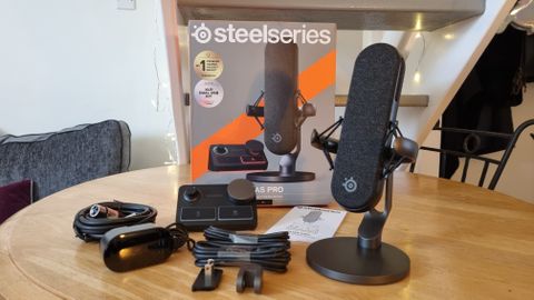 The SteelSeries Alias Pro with Stream Mixer and included cable, on a table with the packaging