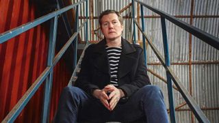Tim Bowness sitting on some steps in a warehouse