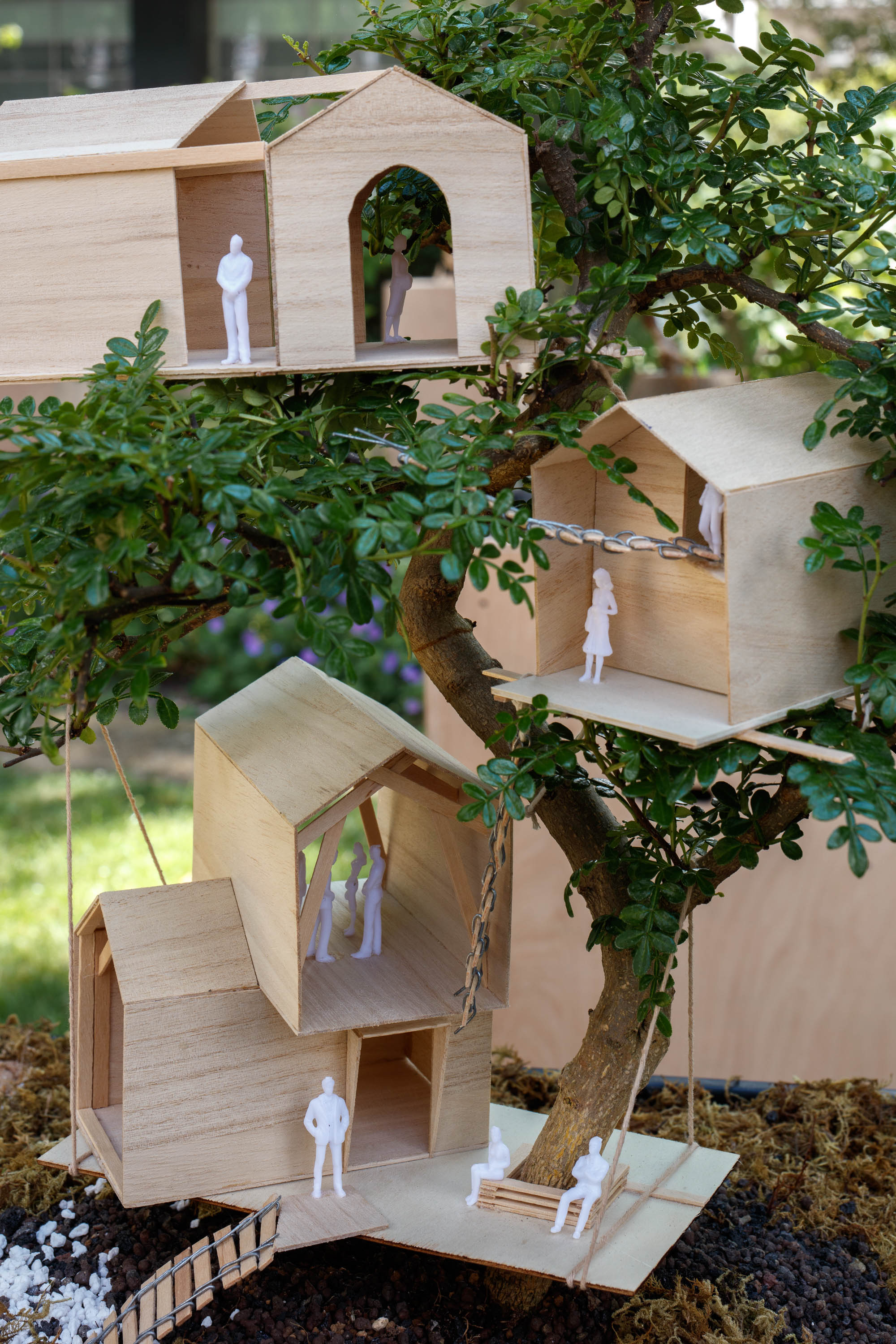 view of miniature houses in a park as part of an open air Bonsai treehouse exhibition in London