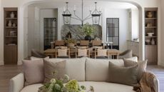 a view from the living room through to an open plan dining and kitchen space with a neutral couch front and center, a layered kitchen with marble backsplash and large island