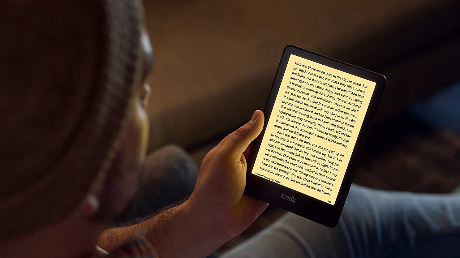 A Kindle Paperwhite (2021) in someone's hand with a warm light on the screen