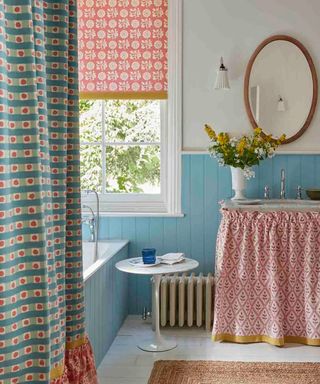 Bathroom with blue paneling and a sink skirt in Vanessa Arbuthnott fabric