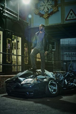 Vincent Hubbard (Richard Blackwood) stands on a crushed car (BBC)