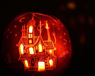 carved pumpkin with haunted house design