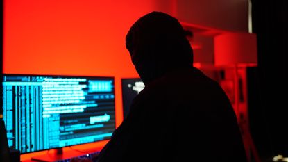 A stock photo of a hacker sitting at a computer. 
