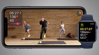 An iPhone and Apple Watch on a grey background during an Apple Fitness Plus workout