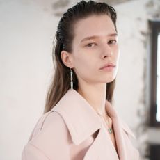 A model backstage at lacoste spring 2025 show wearing clean natural makeup and slicked hair 
