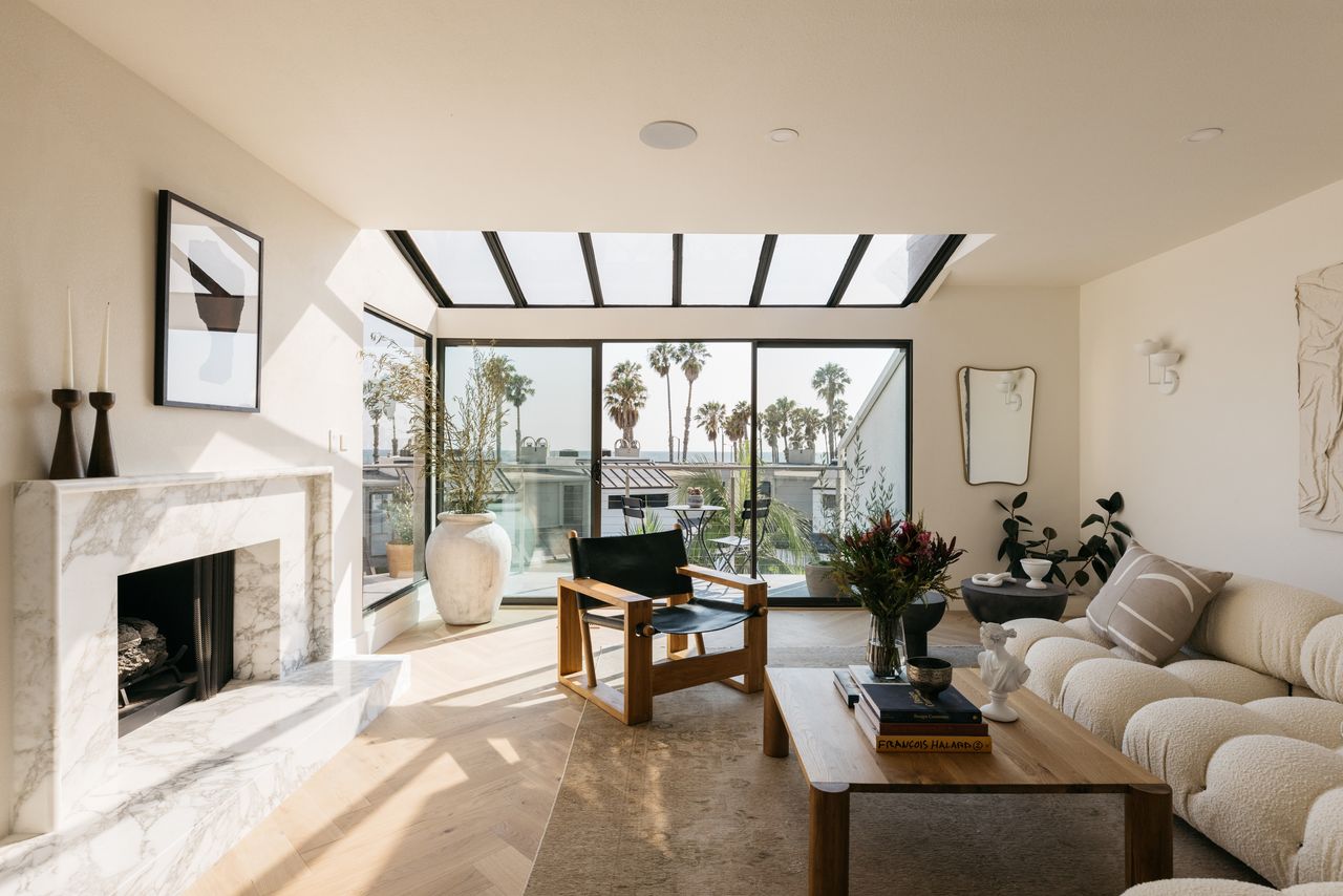 A neutral living room with herringbone flooring and a marble fireplace