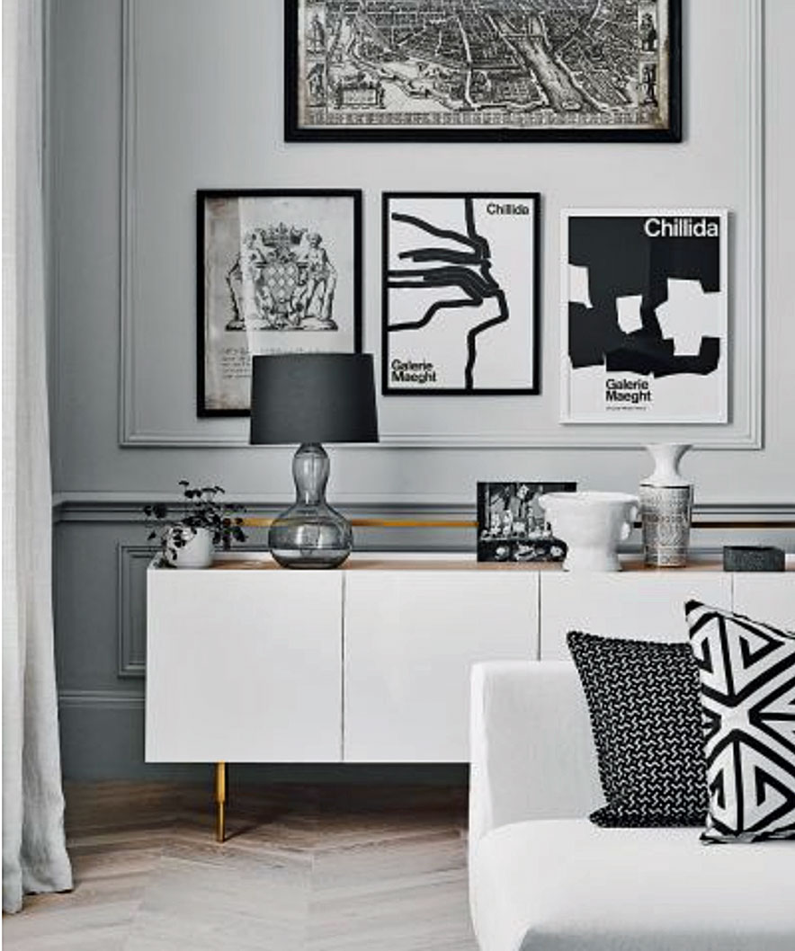 Monochromatic living room color scheme with pale gray walls, white sideboard and black and white decor.