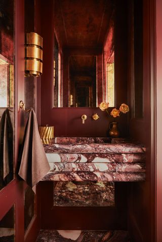 a red powder room with a stacked marble vanity