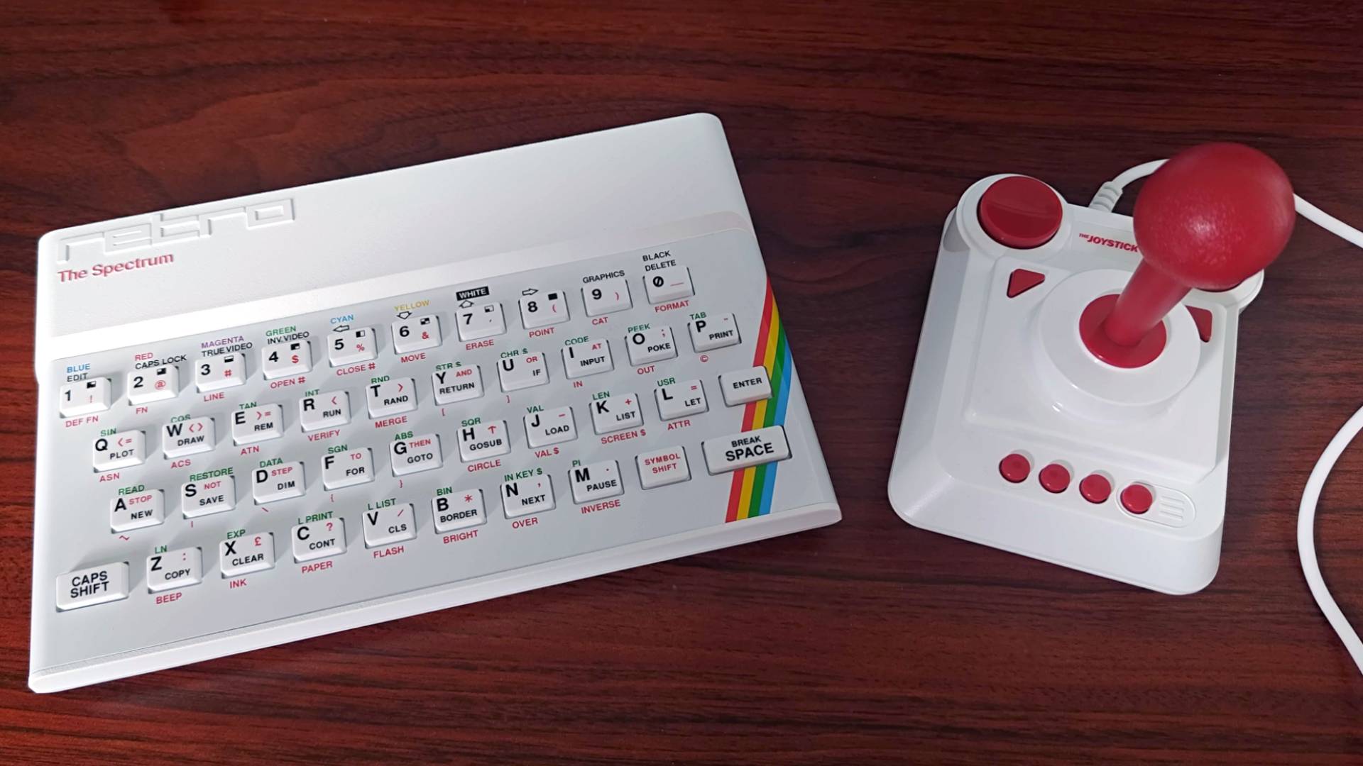 The Spectrum White Edition next to matching joystick on woodgrain desk.