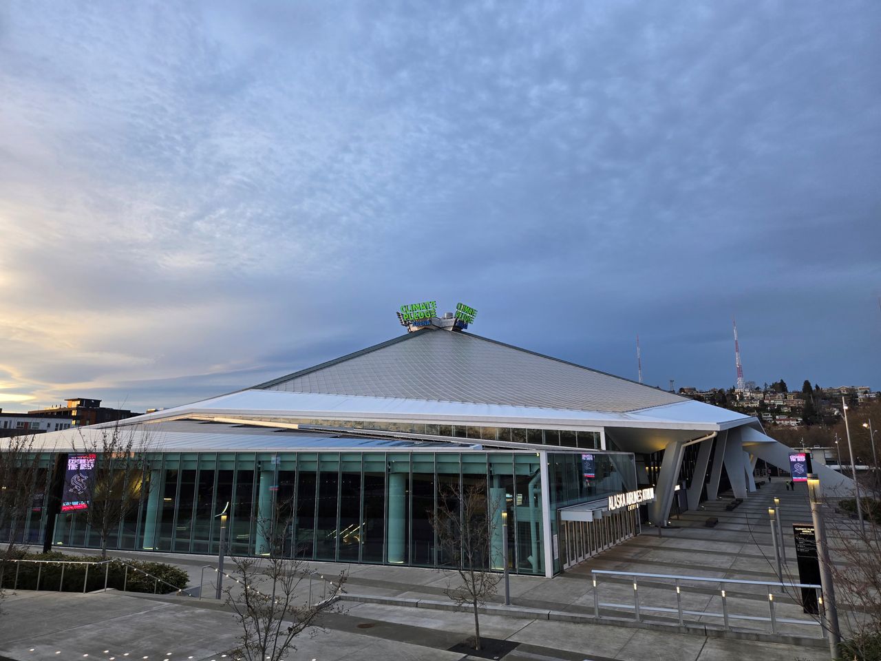 A neon sign on top of a building that reads "Climate Pledge Arena" at 1x