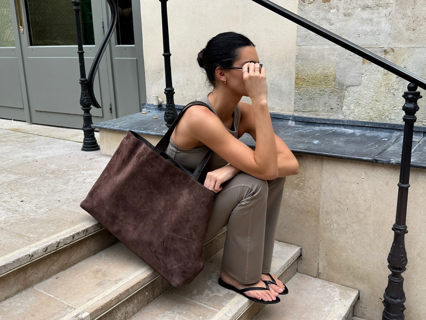 Kendall Jenner wearing a tan Alo workout set, a brown suede tote bag, and black leather flip-flops.