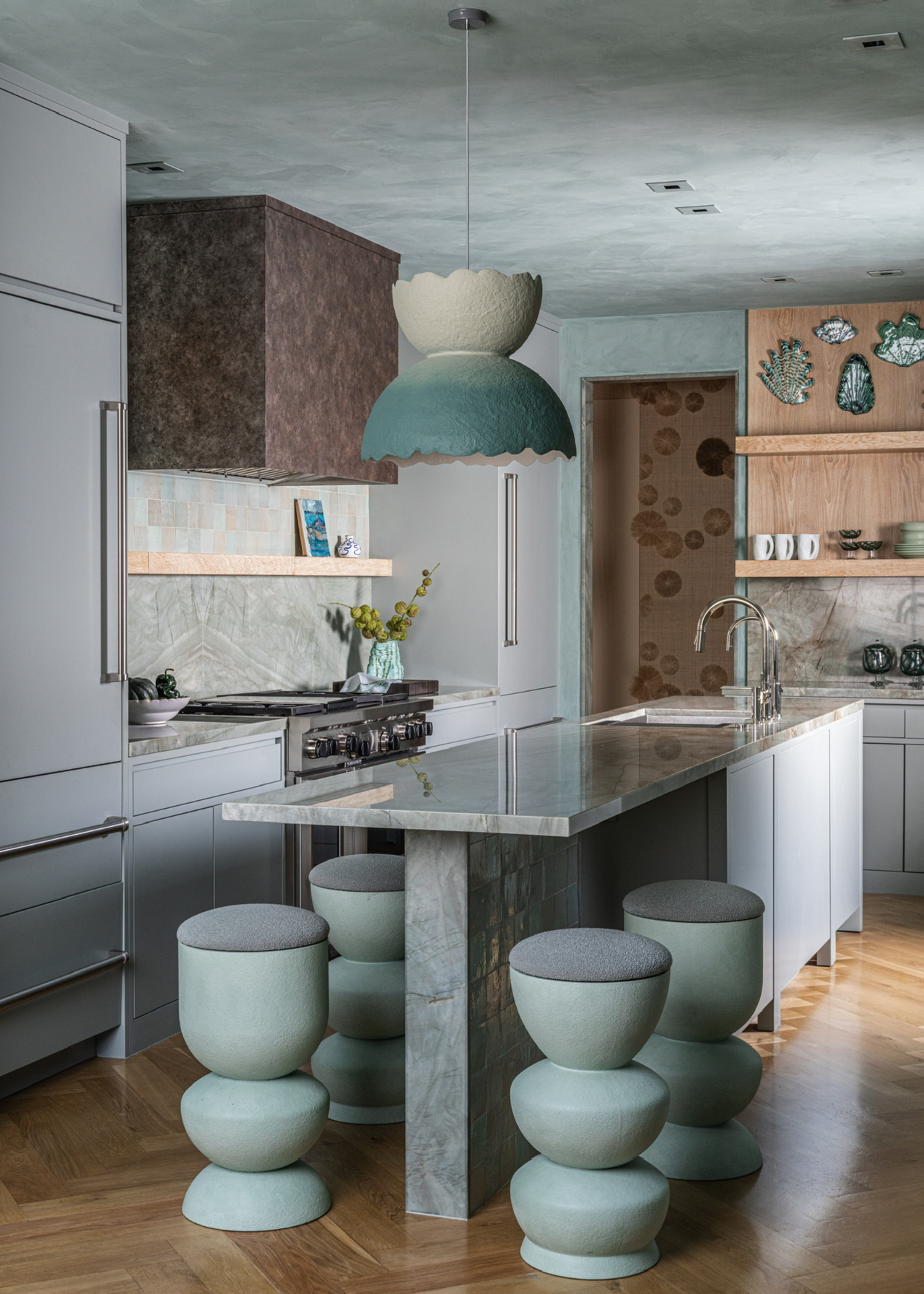 a modern kitchen with kitchen island in pale blue with a unique pendant light and wooden flooring