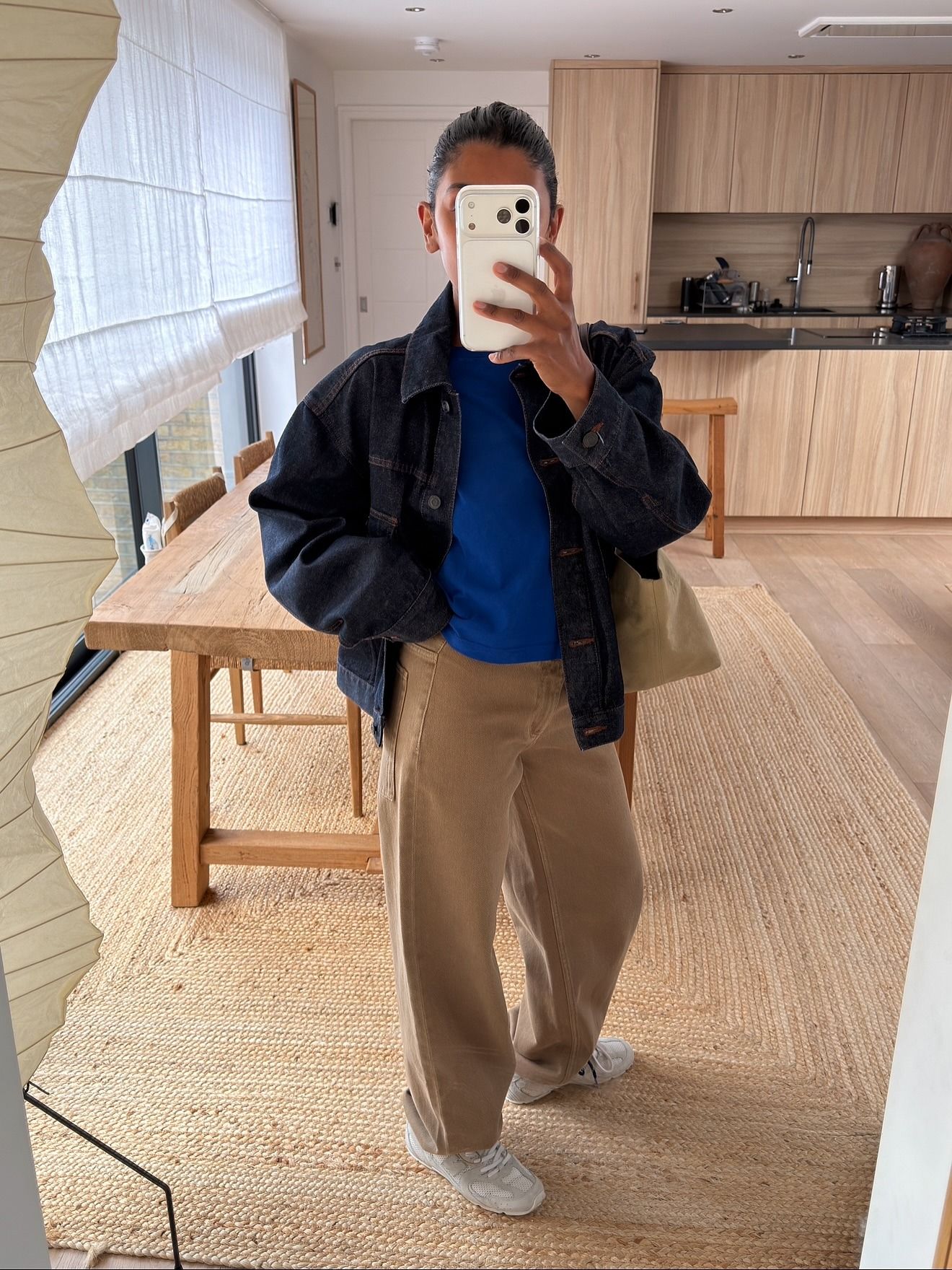 Monik wears a denim jacket, blue tee, sneakers, and beige jeans.