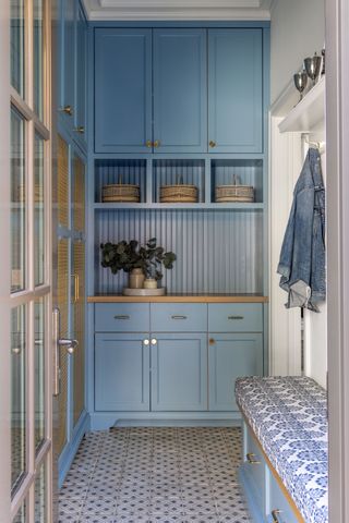 blue built in storage in a mud room with patterned bench seat cushion and tiled floor with French windows visible