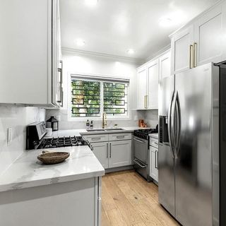 Kitchen with white walls white cabinet and wooden flooring