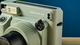 A sage green Fujifilm Instax Wide 400 instant camera