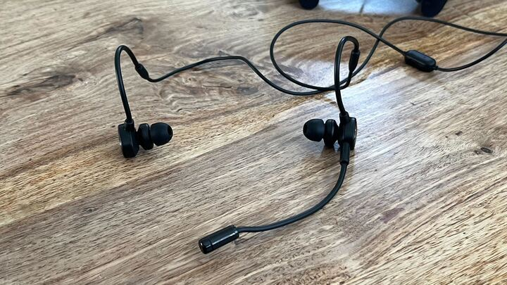 SteelSeries Tusq gaming earbuds on a wooden table.