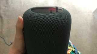 Apple HomePod in a hand, on beige background