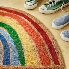 two pairs of shoes in front of a rainbow door mat 