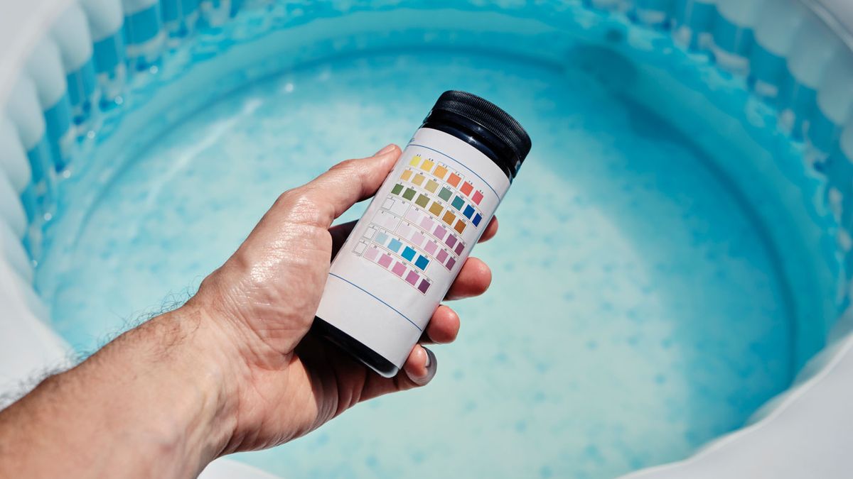 Hot tub supplies: Image shows a hand holding a pH tester over a hot tub.