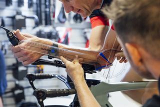 Bike fitter checking the angle of a male cyclists' arms while in a TT position
