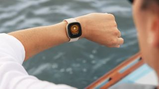 Een vrouw op een boot checkt haar Fitbit Sense-horloge