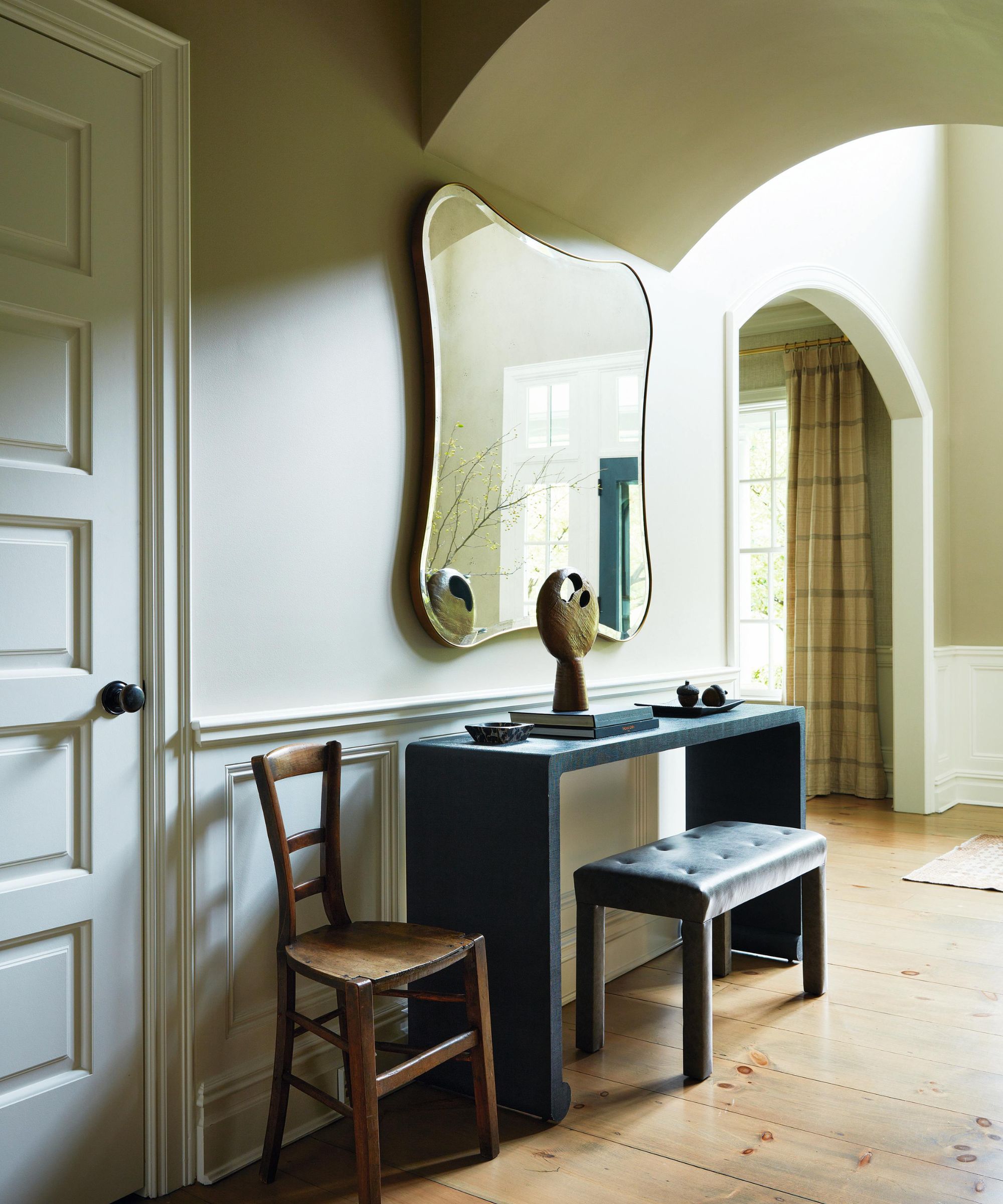 a soft neutral light hallway with arched walkways and a console table with a curved mirror hung above
