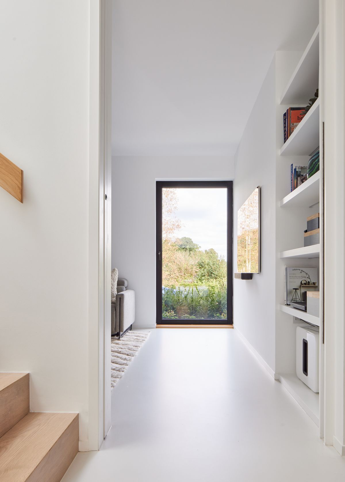 A minimalistic hallway with white walls and a large floor to ceiling window in the background