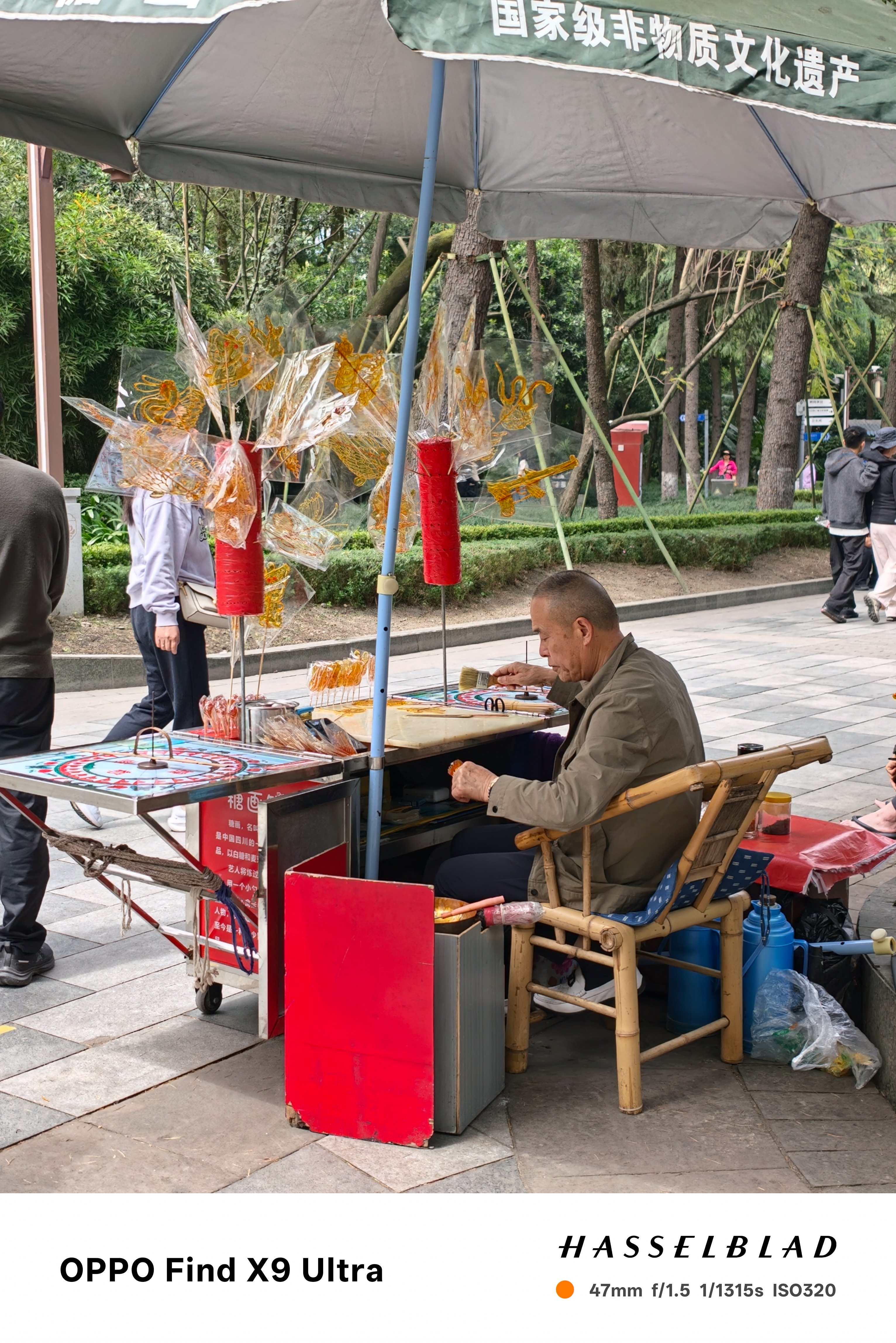 Street vendor making sugar art beneath an umbrella in a park