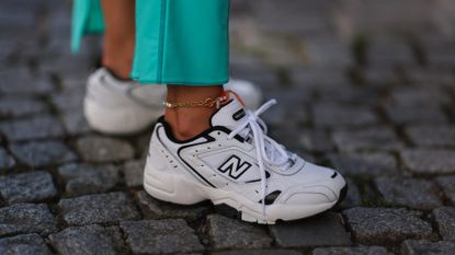Karin Teigl wearing New Balance white and navy blue sneaker and Jacquemus colorful blue long skirt on August 04, 2022 in Vienna, Austria. 