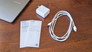 A closeup of the USB-C cable, outlet adapter, and manuals that come with the Samsung Galaxy Book5 Pro