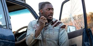 Beast star Idris Elba stands next to a 4x4 with a shattered window