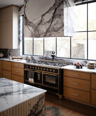 wooden kitchen with large marble range cooker hood and fluted marble island