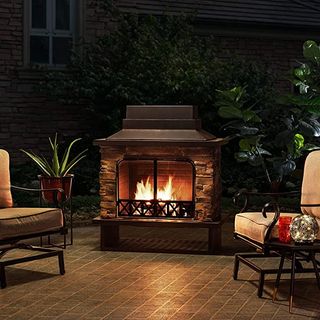 Outdoor fireplace on tiles with two chairs and a plant