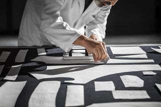 Man in factory cutting out pattern pieces of Loro Piana Denim Silk
