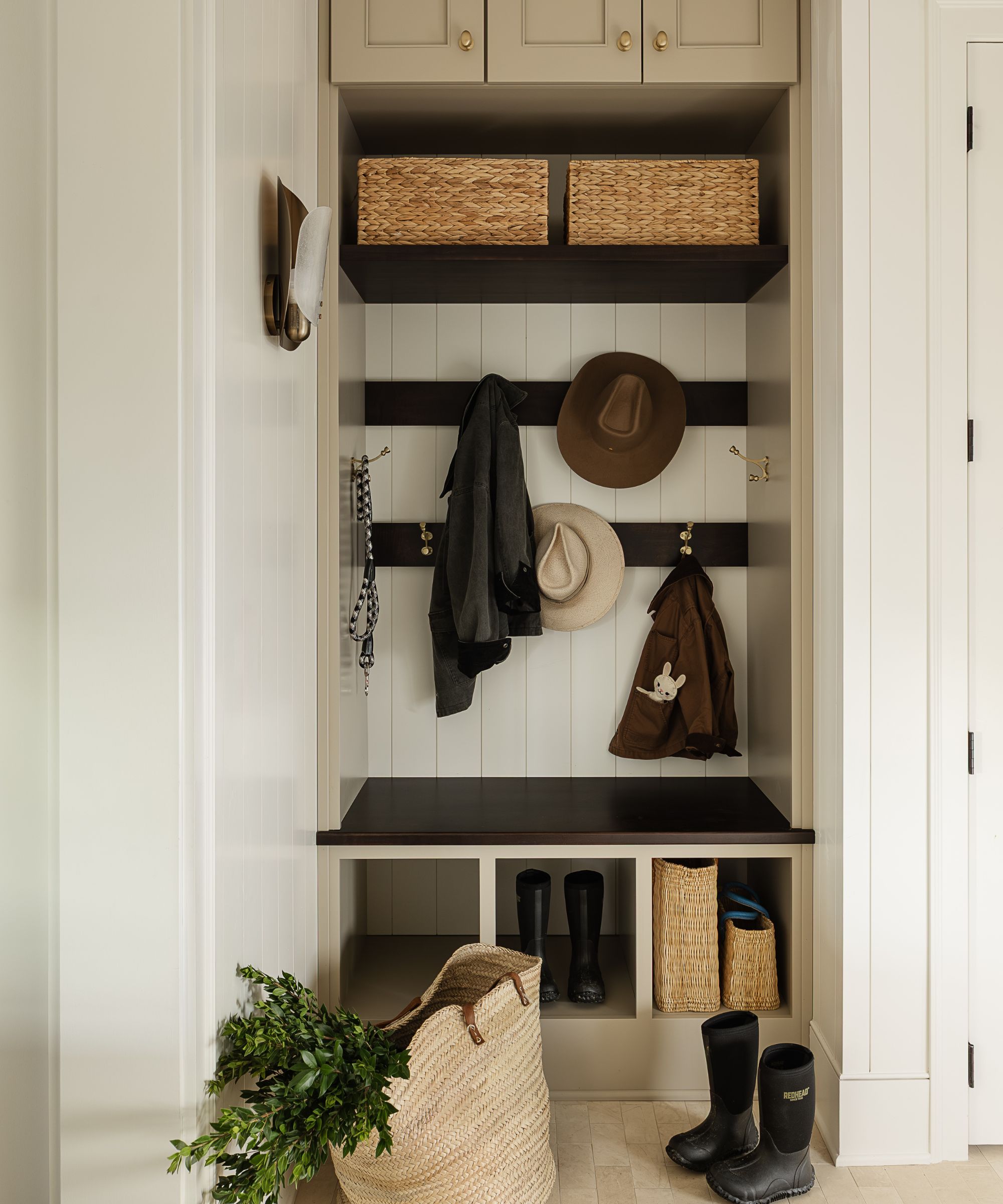 a tiny mudroom with paneled walls, hooks for hats, baskets, and a bench seat with built-in boot storage