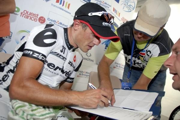 Simon Gerrans signs some paperwork for the UCI chaperone.