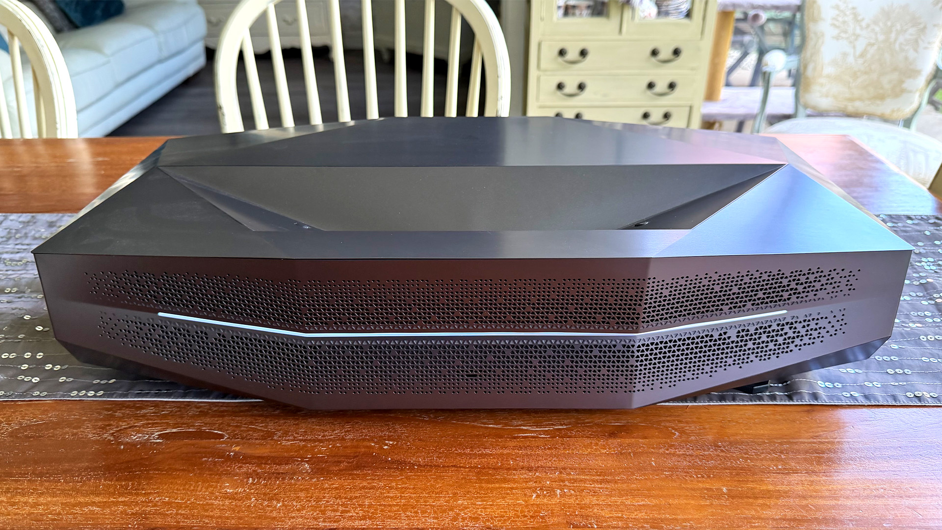 AWOL Vision Aetherion Max ultra short throw projector on wooden dining table with chairs in background