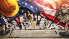 American flag on wood table with hard hat, tools and gloves