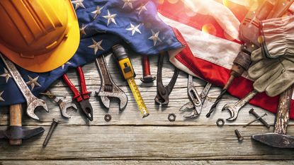 American flag on wood table with hard hat, tools and gloves