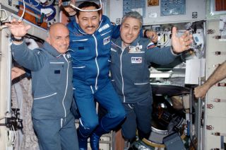 Privately-funded space tourist Dennis Tito, at left, with his Soyuz TM-32 crewmates, Roscosmos cosmonauts Talgat Musabayev and Yuri Baturin, on the International Space Station in May 2001.