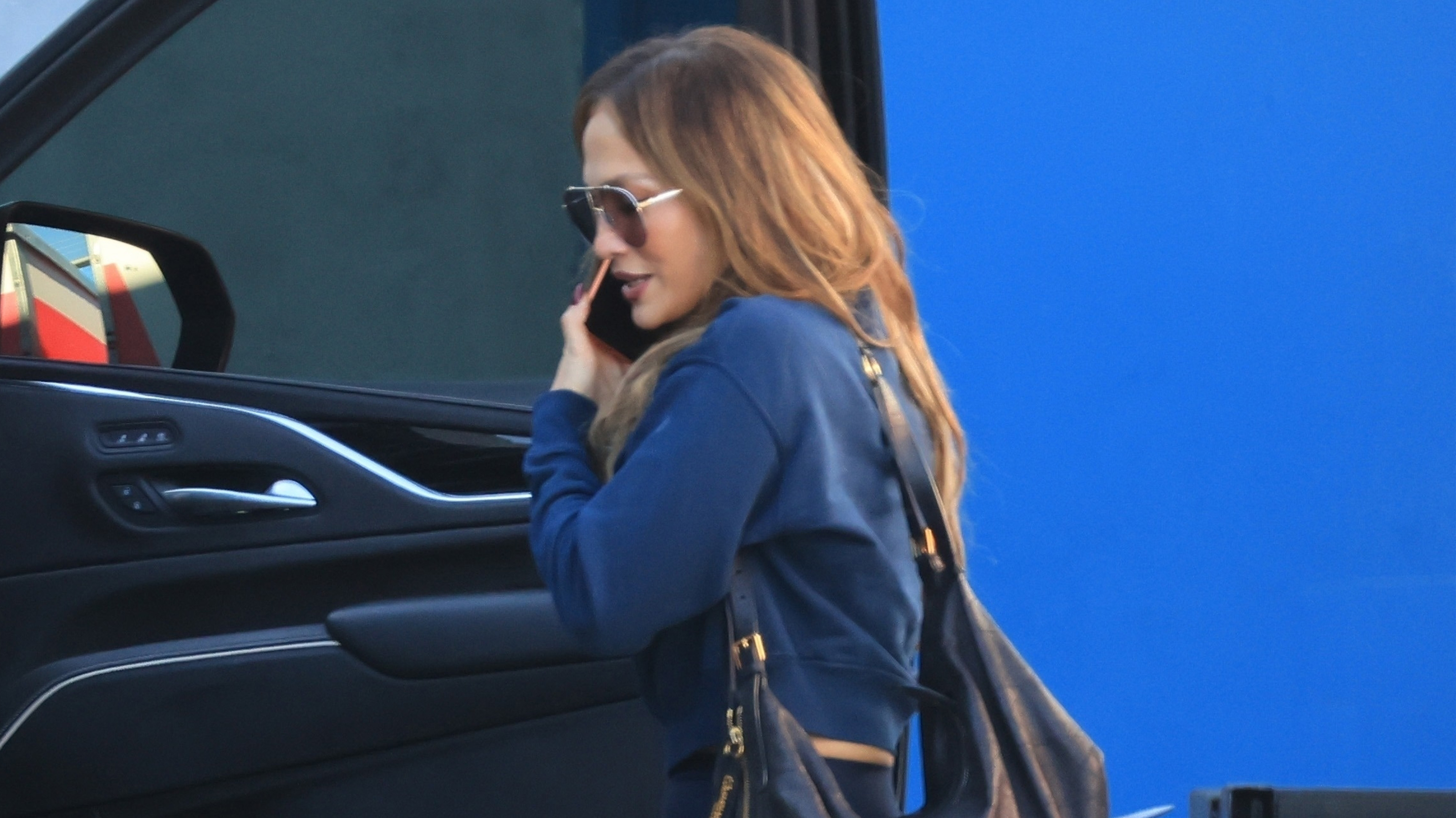 Jennifer lopez wears oversize sunglasses and a navy sweatshirt.