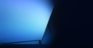 A Surface Pro on a blue background, shooting light blue light from the screen.