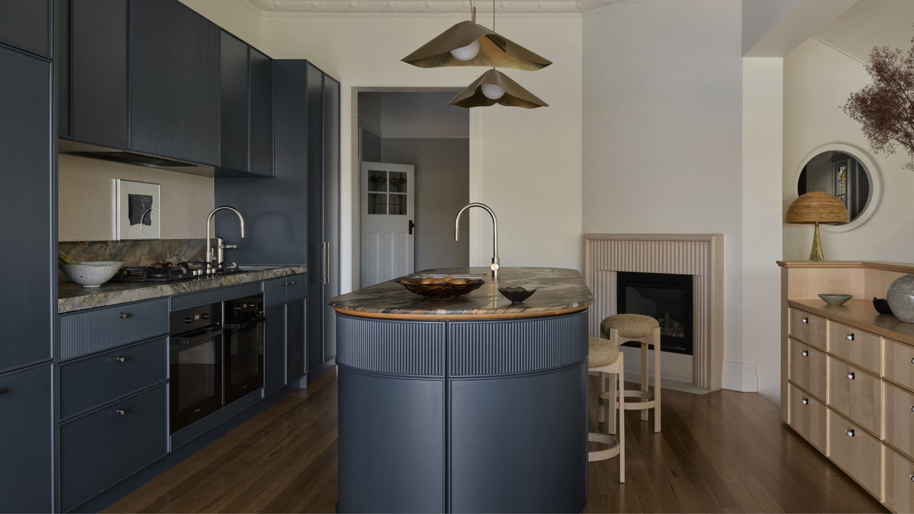 a traditional style kitchen with navy cabinetry and contemporary features