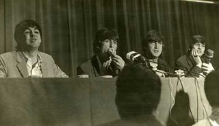 The Beatles seated at a press conference