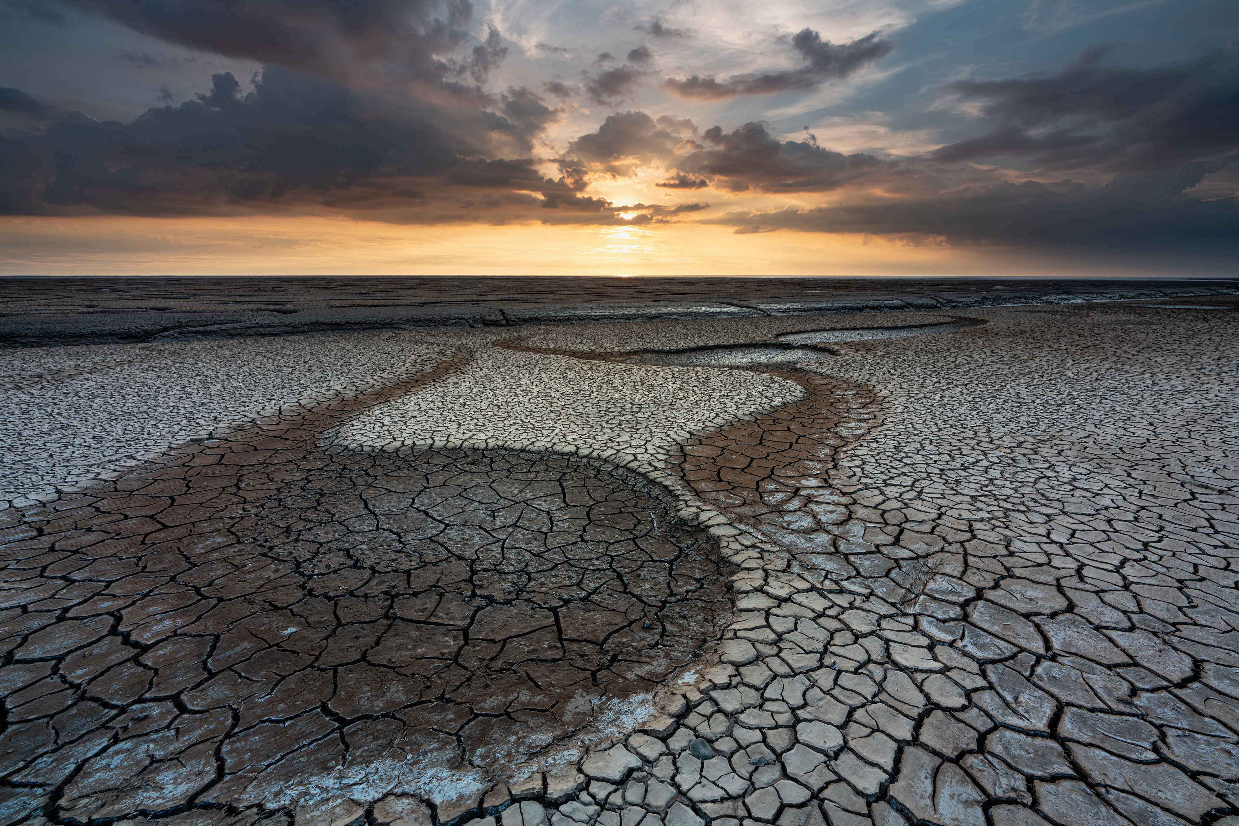 A sunset over some cracked flatlands