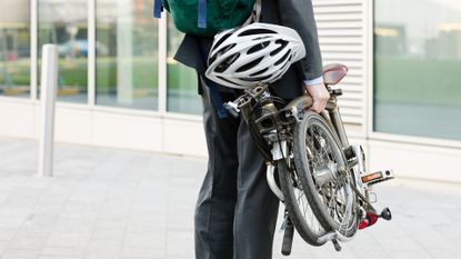 Image shows a person holding a folding bike.